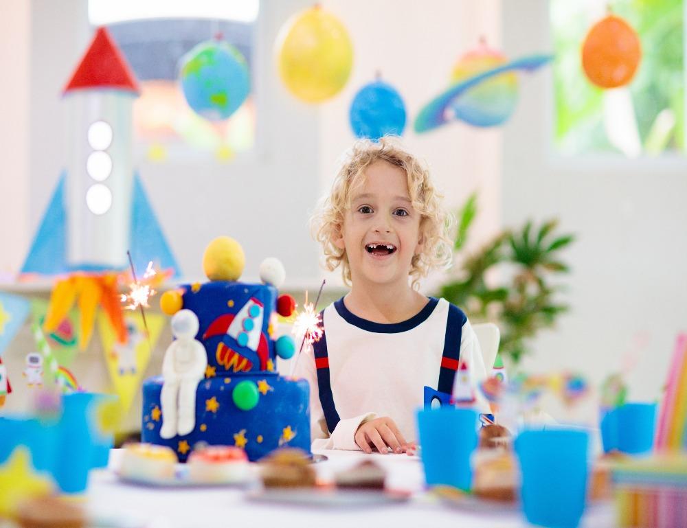 Young boy sat at a table with his space birthday cake in front of him
