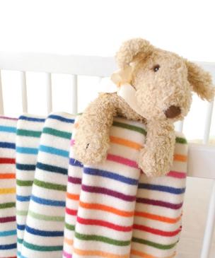 selection of lambs-wool baby blankets hanging on cot