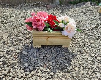artificial flowers in a decking planter on gravel