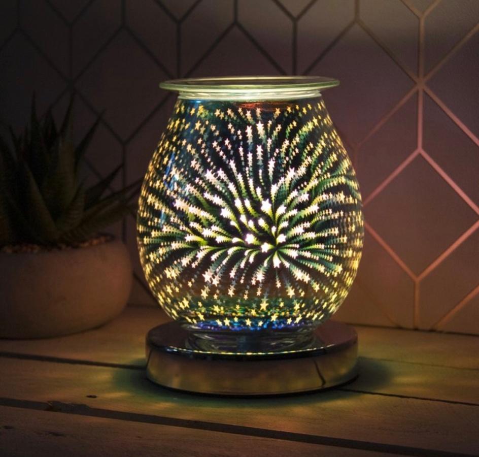 Glass wax warmer glowing with white/yellow 3d shooting stars and a chrome circle base.