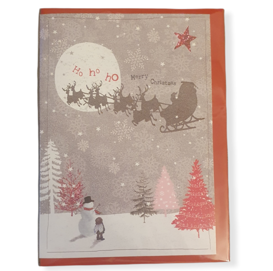 Grey card, white moon top left, with a dark Reindeer & sleigh silhouette through it. Snow on the ground with pink, white and a black tree, snowman and a boy standing by a pink tree bottom left looking up at the sleigh in the sky.