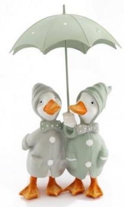 Pair of white ducks, orange noses, orange webbed feet, sage green rain coats, hoods up, holding a sage green umbrella above heads.