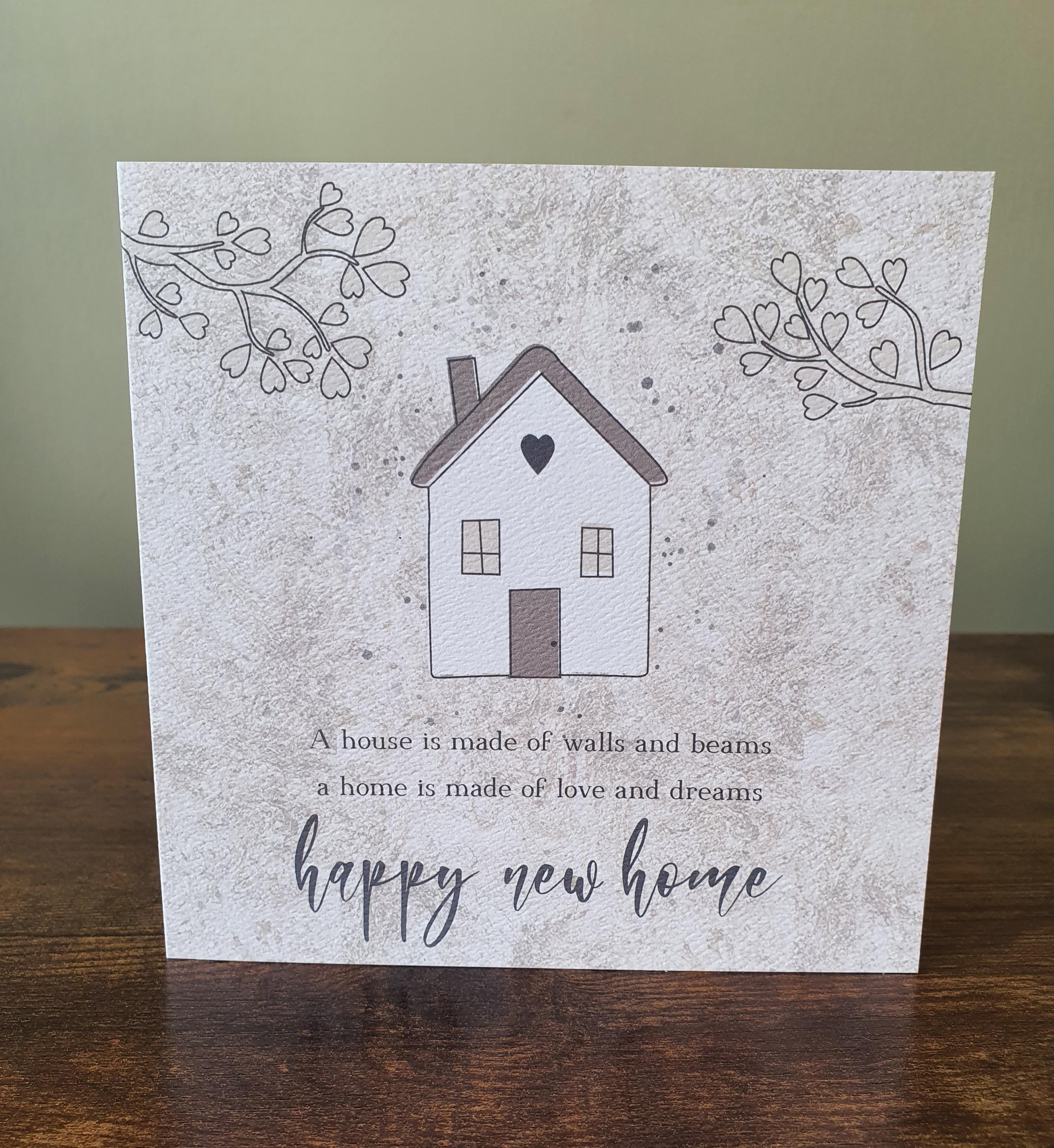Square light beige card, a house and trees printed onto it, text ' A house is made of walls and beams, a home is made of love and dreams, Happy New Home'.