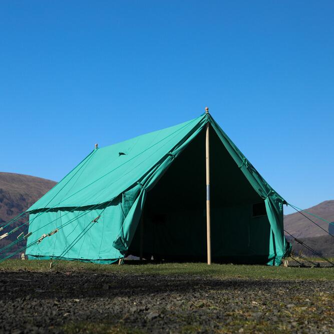 Green patrol tent pitched on grass