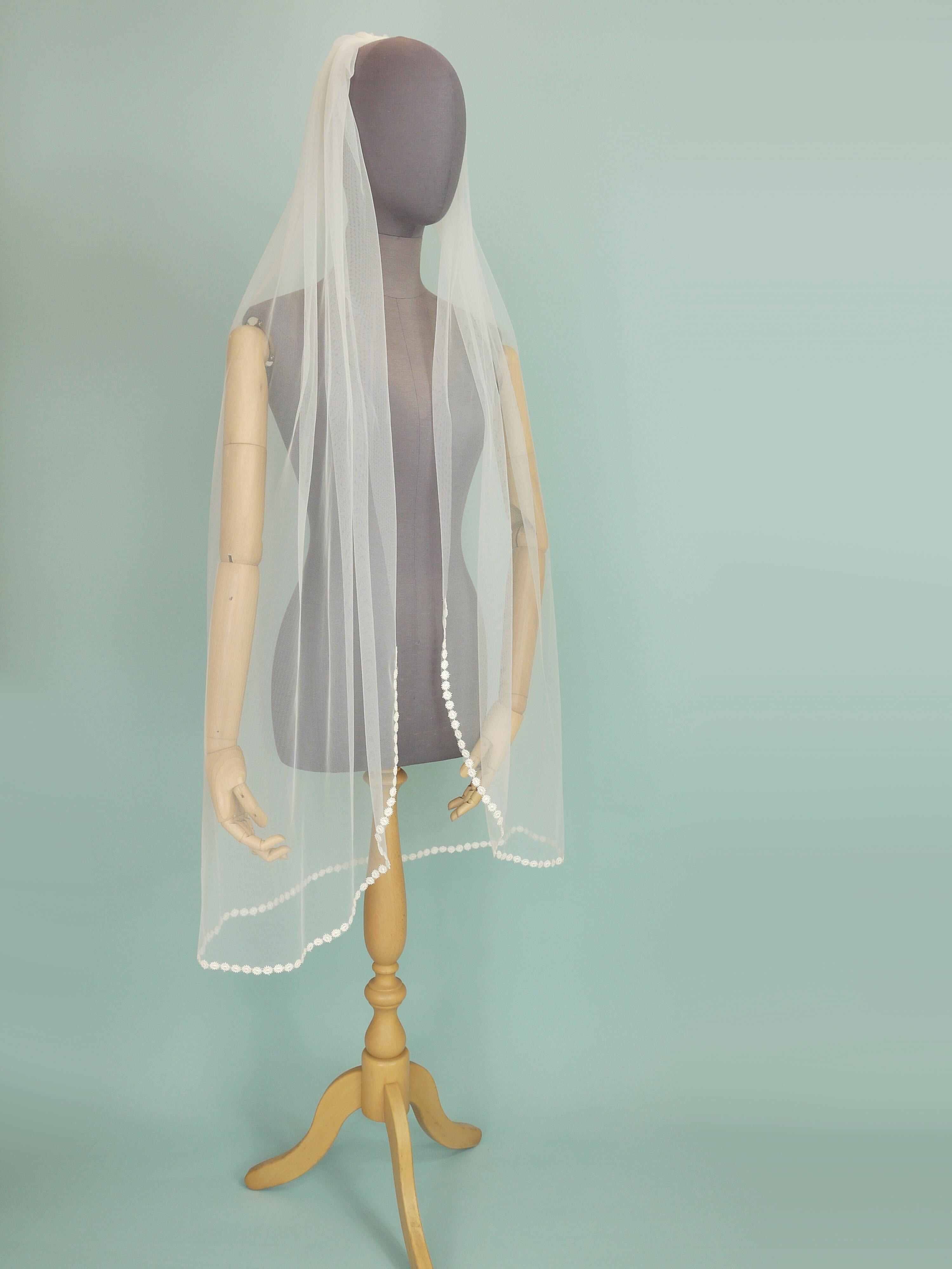 Ivory coloured wedding veil with a floral trim on the bottom edge