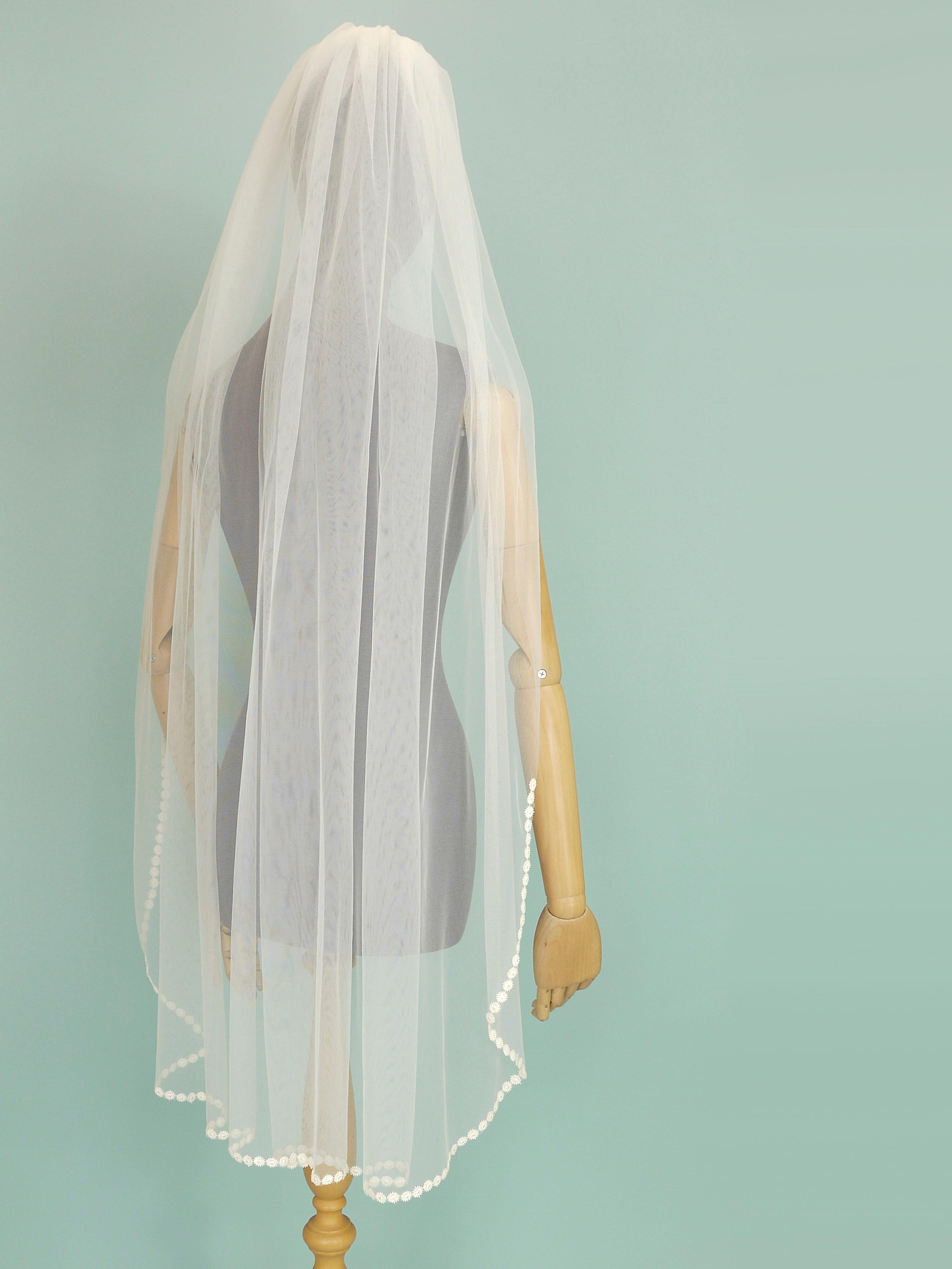 Ivory coloured wedding veil with a floral trim on the bottom edge