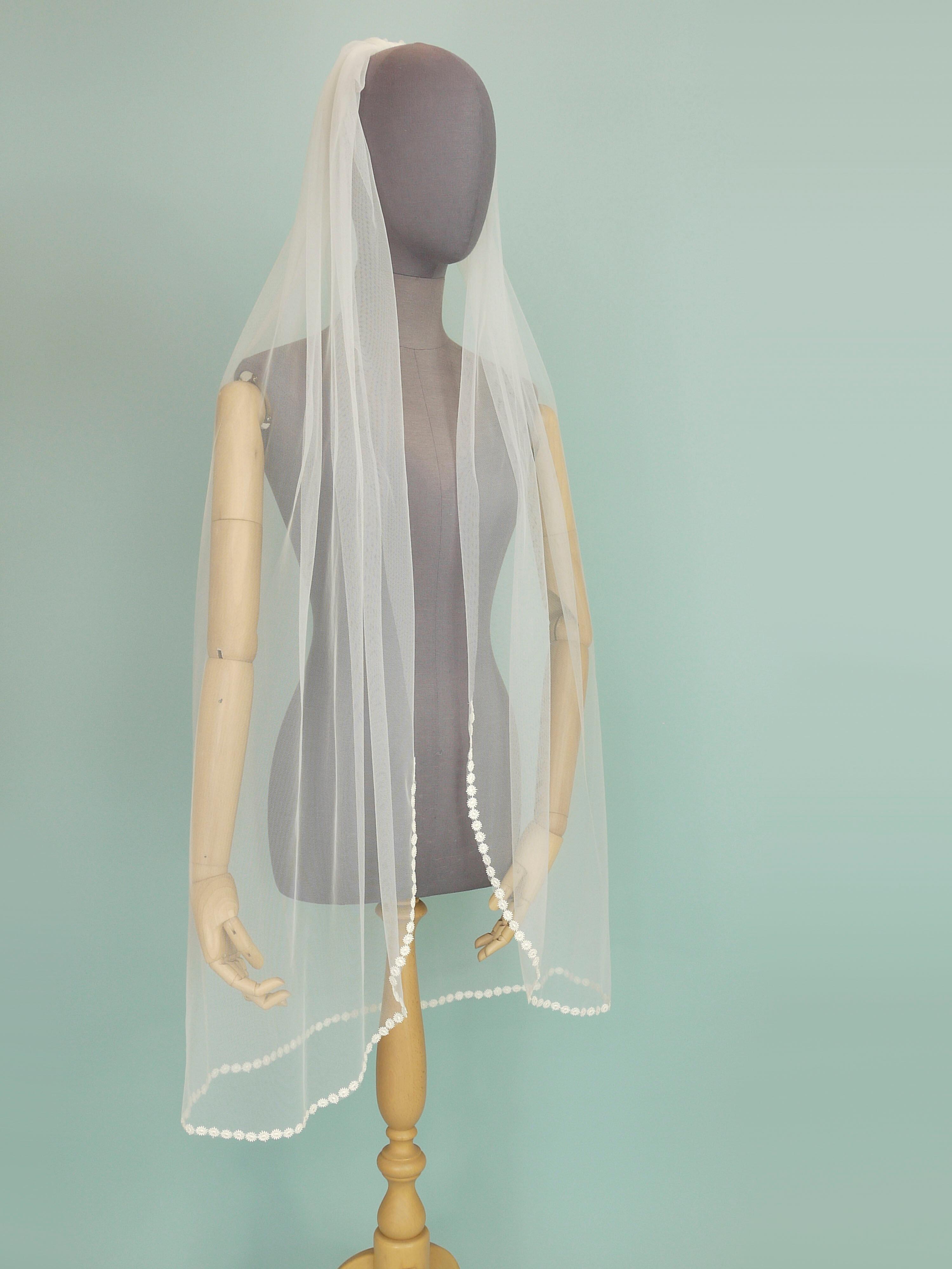 Ivory coloured wedding veil with a floral trim on the bottom edge