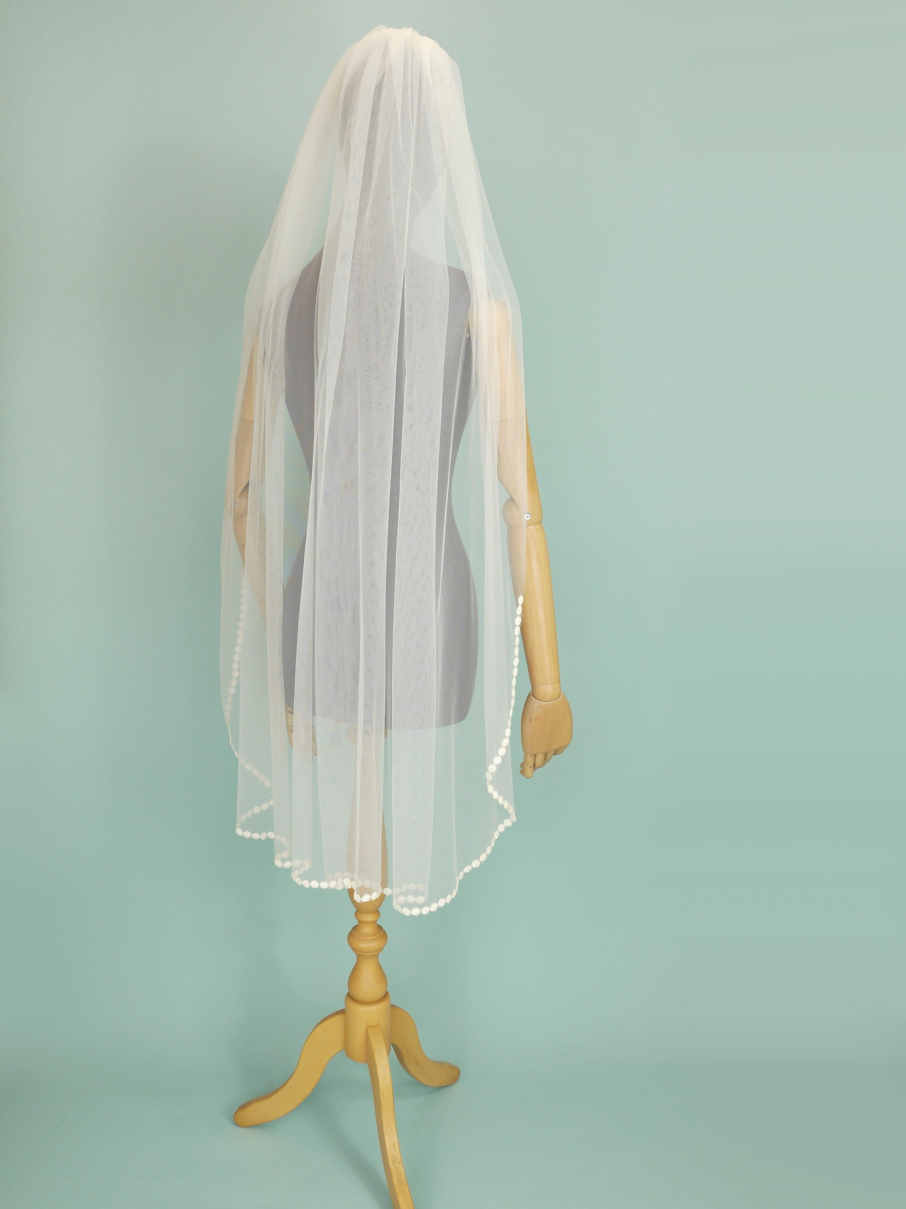 Ivory coloured wedding veil with a floral trim on the bottom edge