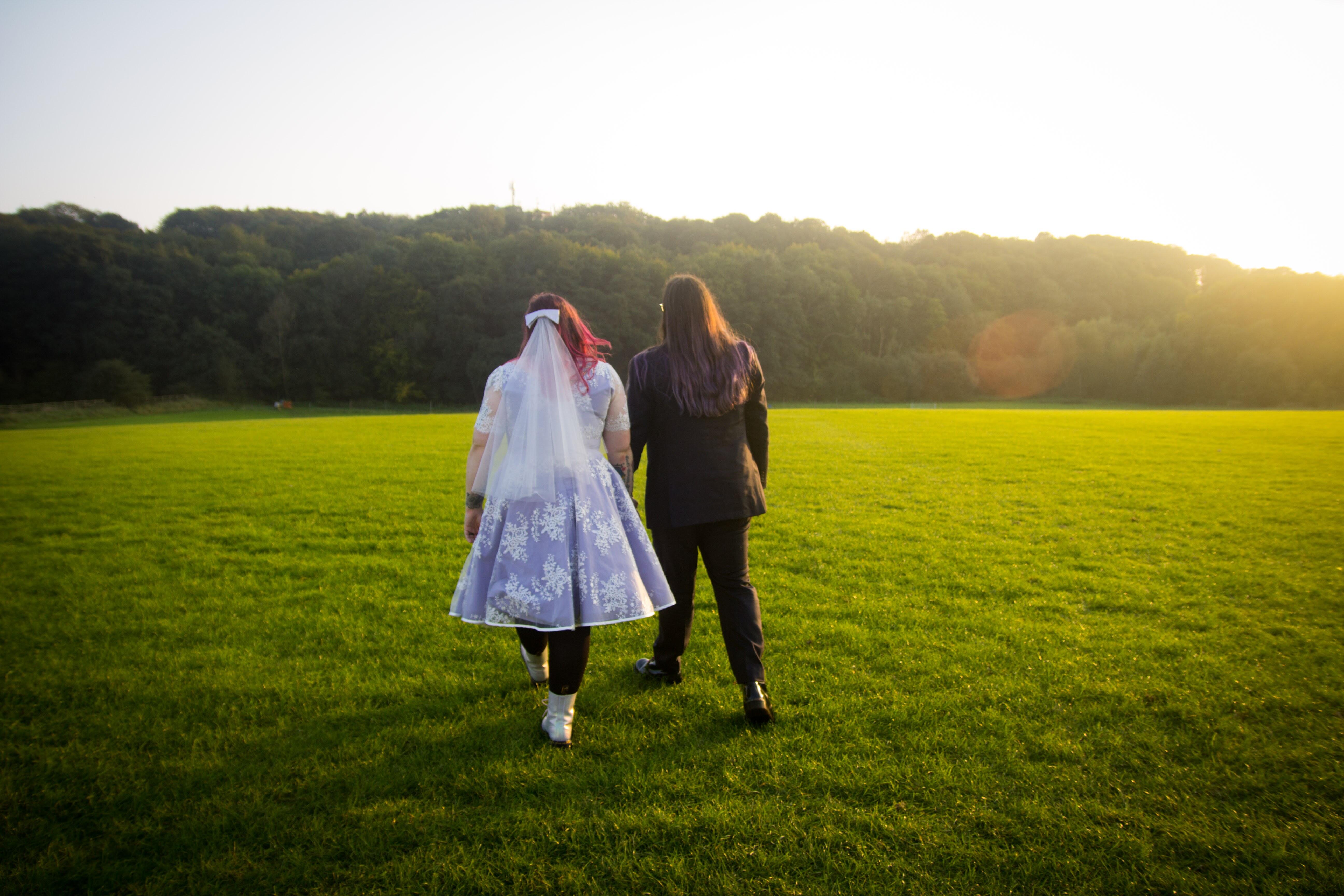 Alternative plus size bride walking into the sunset wearing bespoke lavender lace wedding dress made by Dig For Victory