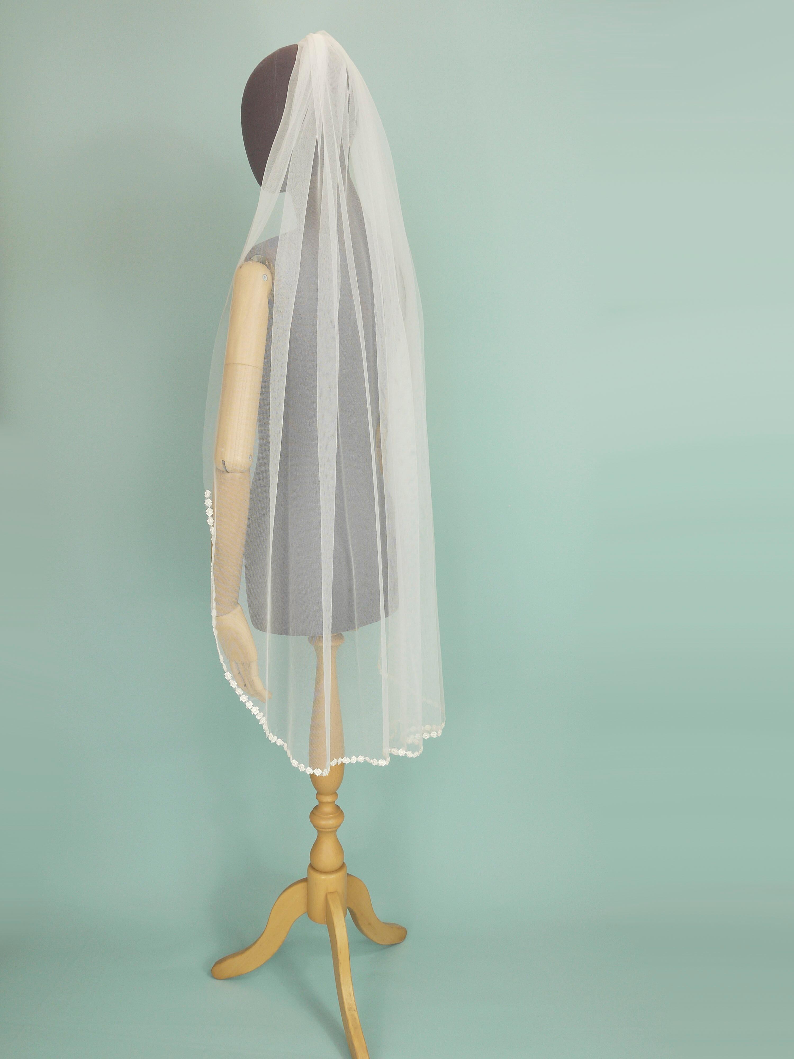 Ivory coloured wedding veil with a floral trim on the bottom edge