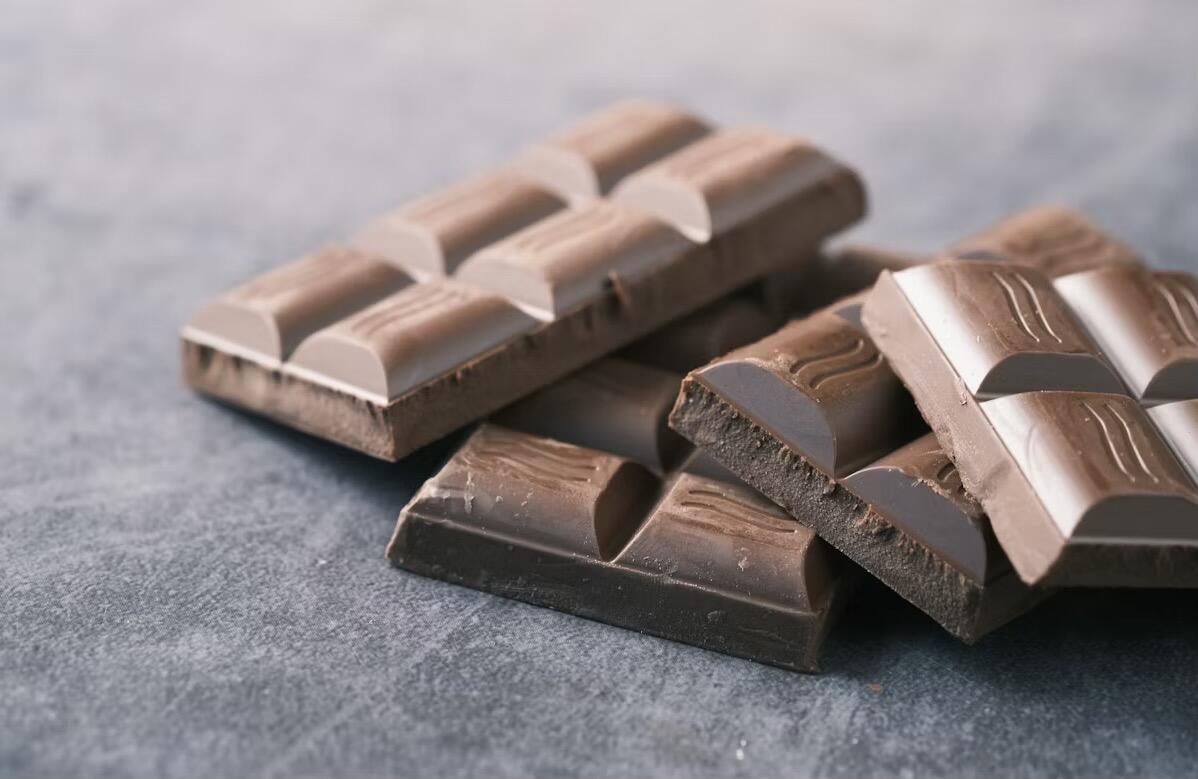 Two chocolate bars on a grey background, showing smooth milk chocolate and dark chocolate varieties, displayed side by side