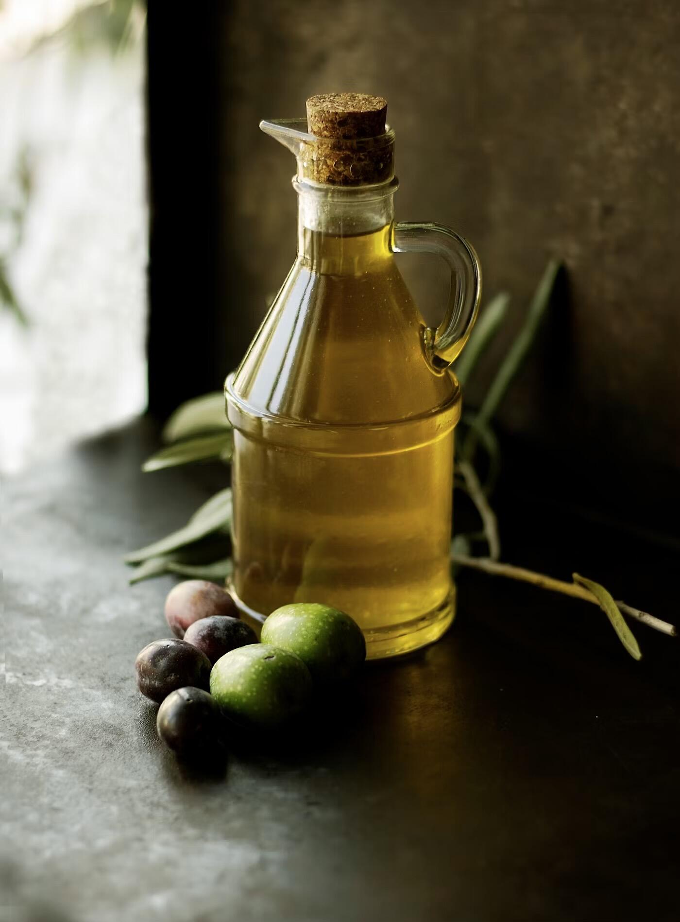 A glass bottle full of oil on a dark oak table