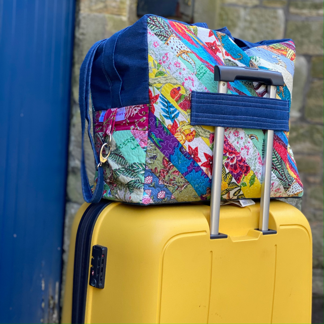 Denim and patchwork flightbag sitting on top of hard back suitcase