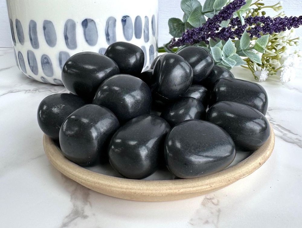 shungite black tumble stones on a plate, the holistic hamper crystals online shop UK