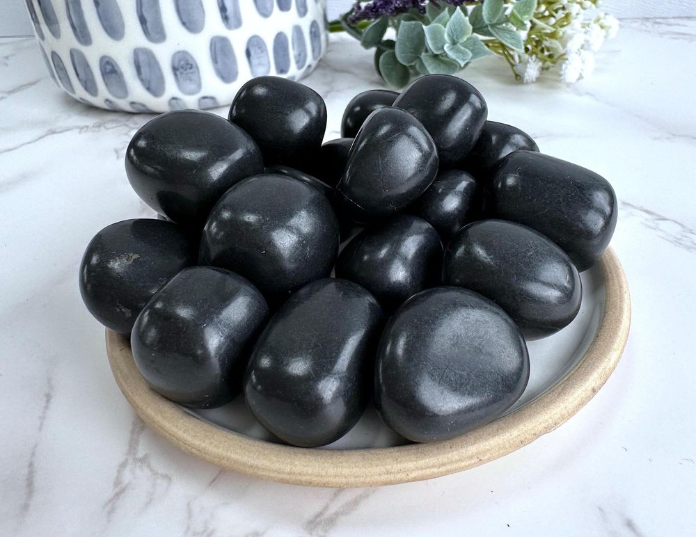 shungite black tumble stones on a plate, the holistic hamper crystals online shop UK