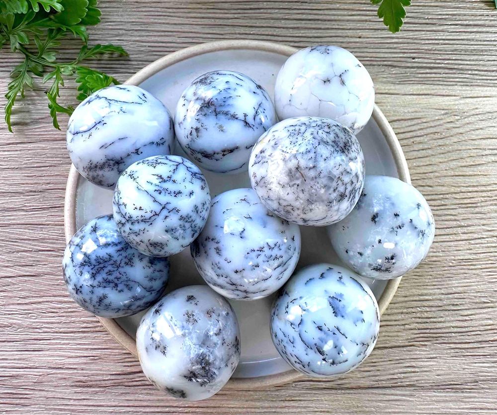 merlinite dendritic white opal crystal tumble stones on a dish