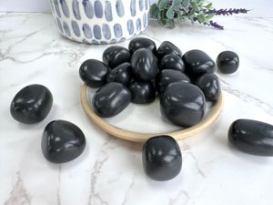Shungite black tumble stones on a plate scattered about