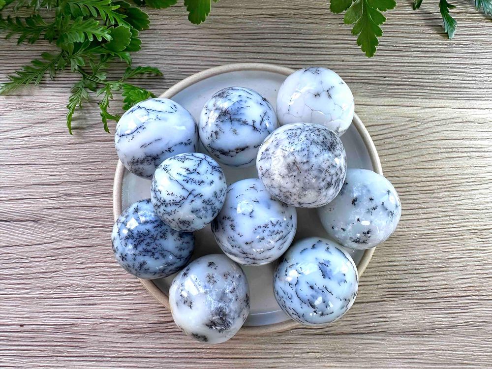 merlinite dendritic white opal crystal tumble stones on a dish