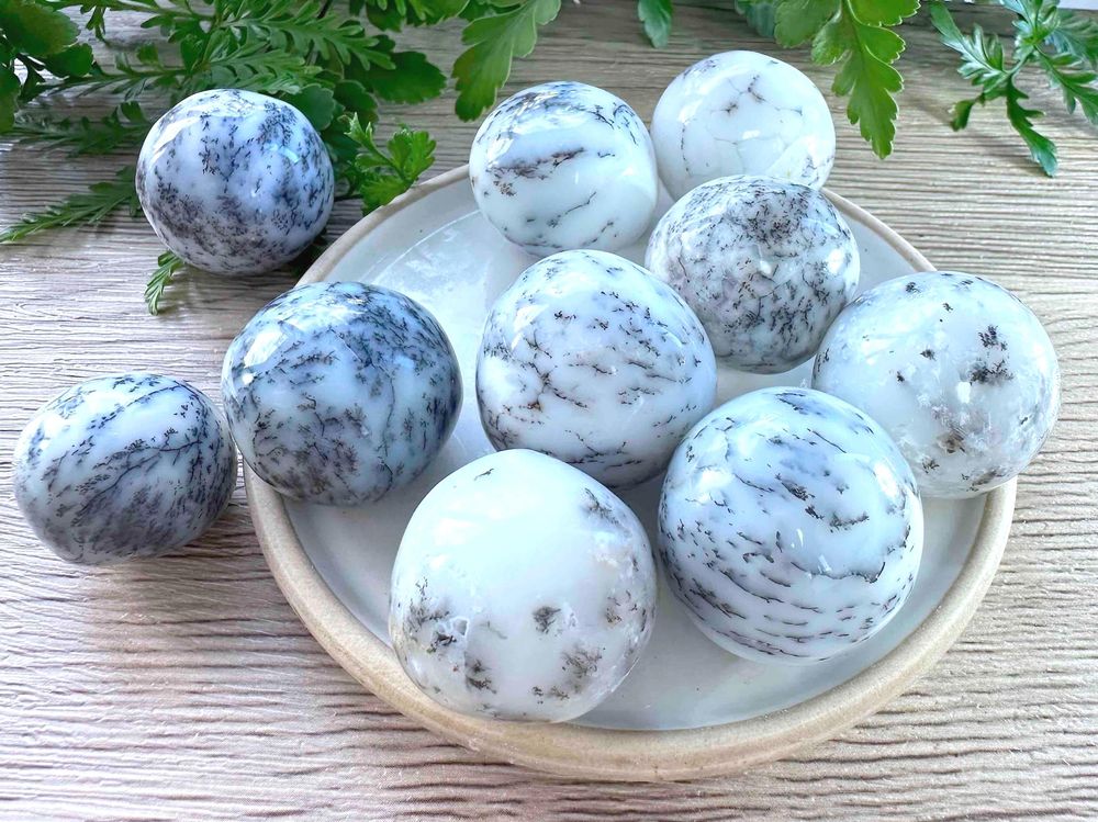 merlinite dendritic white opal crystal tumble stones on a dish