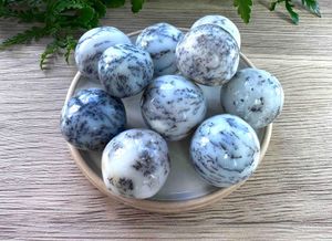 merlinite dendritic white opal crystal tumble stones on a dish