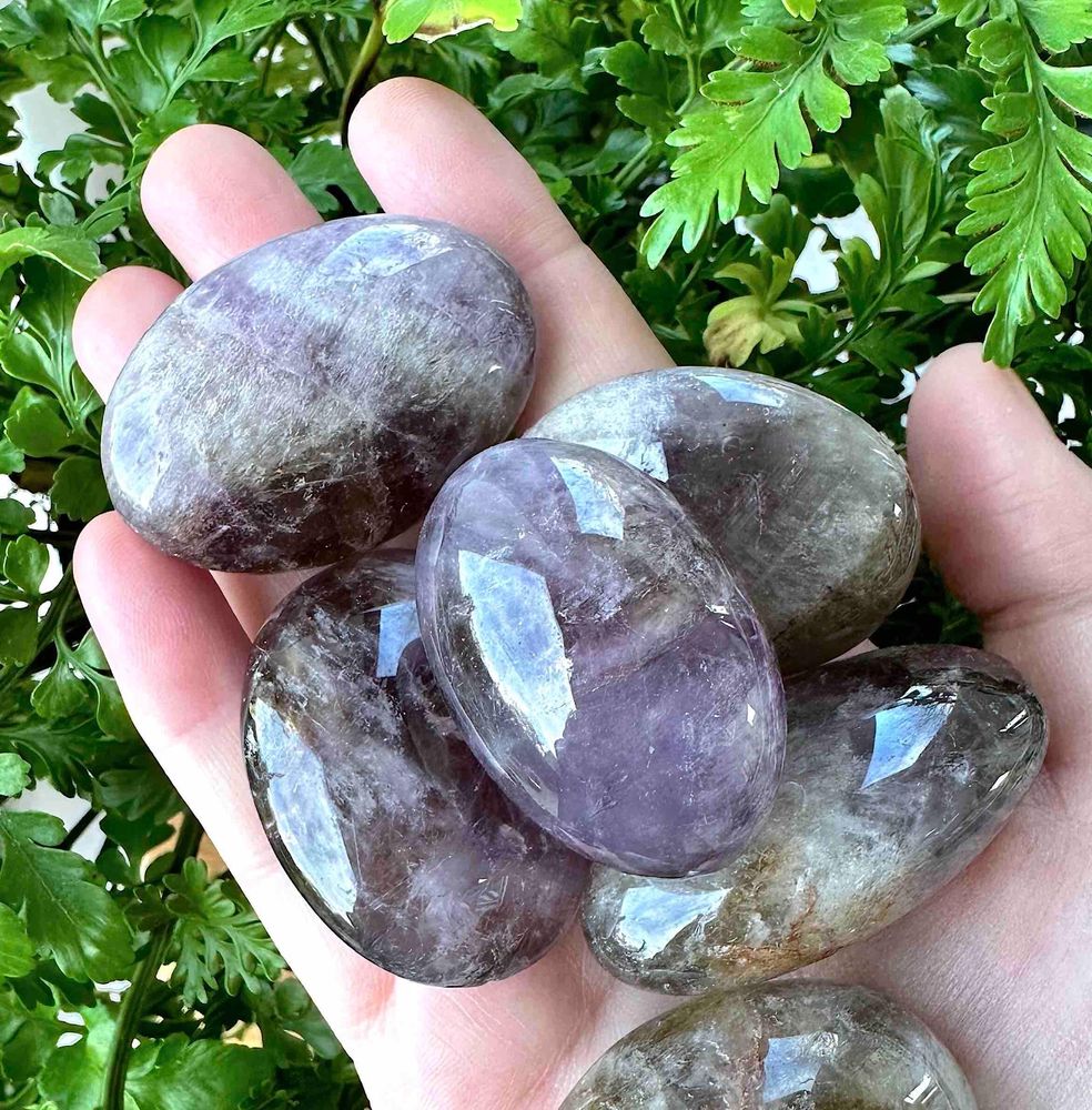large oval ametrine tumbles stones in a hand