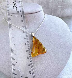 triangular genuine Amber sterling silver pendant on a chain with ruler to show size