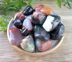 sardonyx tumble stones in oranges, browns and blacks on a dish
