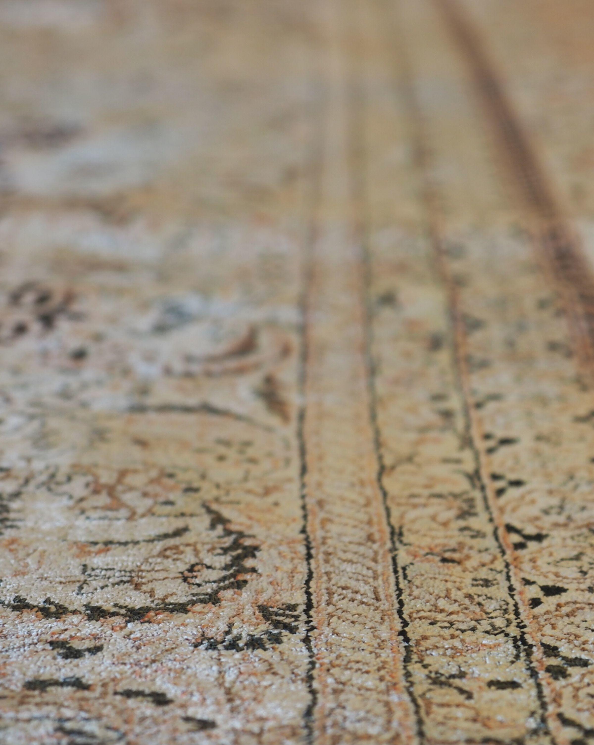 Close up view along the border of a shiny silk rug with a fringe along the edge.