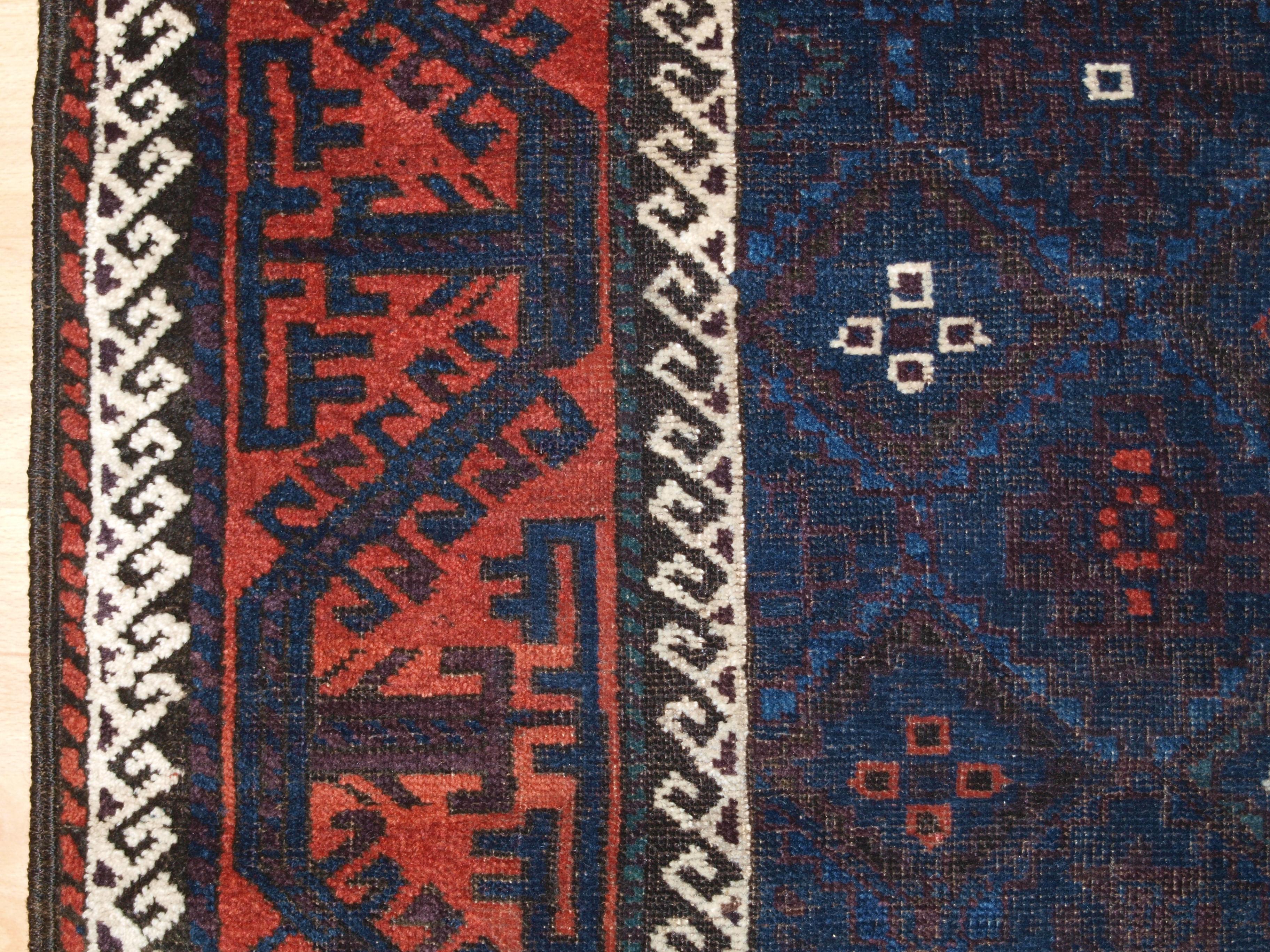 Red geometric contrasting border of antique baluch rug