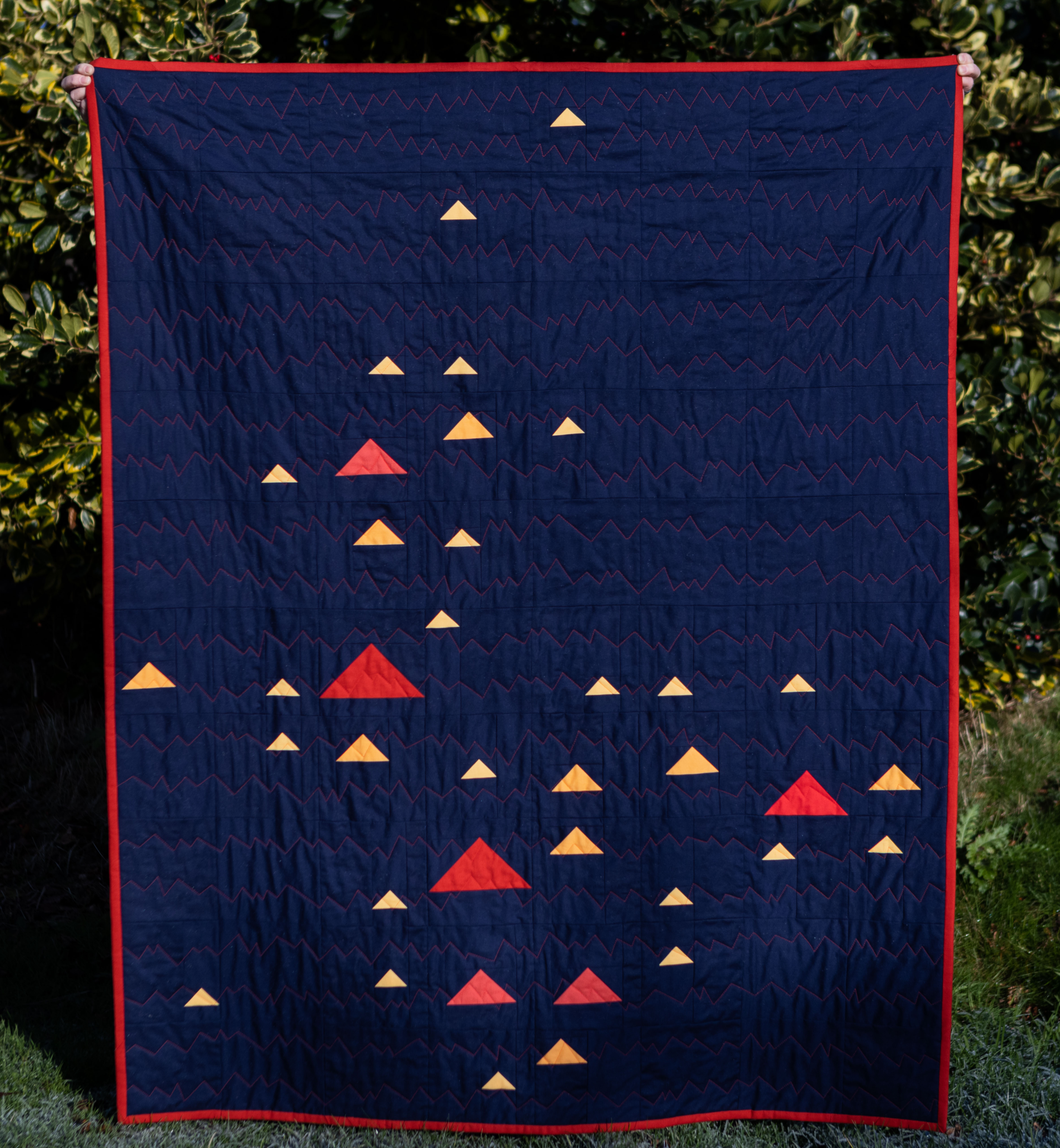 Full Monadh quilt in dark blue with flying geese in red/orange/yellows