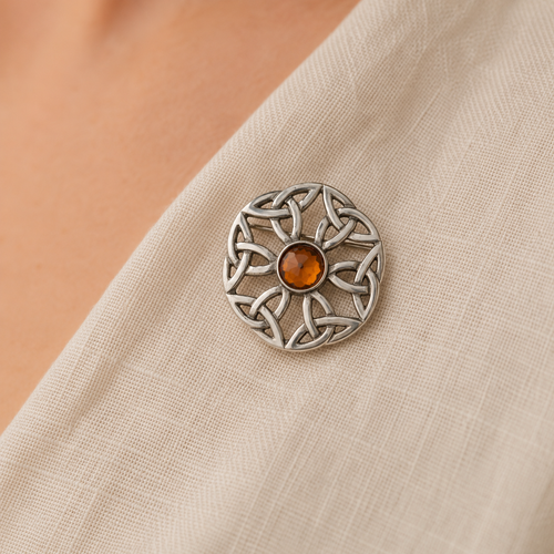 Pewter brooch on textured linen fabric with Amber coloured Gem in the centre
