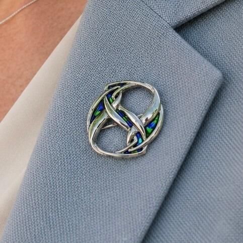 An Archibald Knox style pewter brooch featuring intertwined Art Nouveau Celtic entrelac bands inlaid with vibrant blue and green enamel