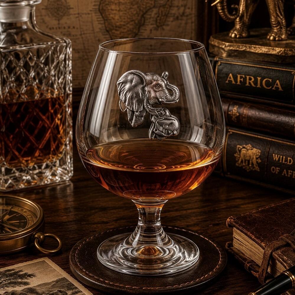 Crystal brandy glass with pewter elephant emblem, partially filled with amber liquid