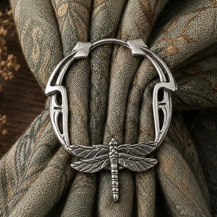 Art Nouveau inspired pewter scarf ring featuring an intricate dragonfly design at the base, cinching a patterned olive green fabric scarf
