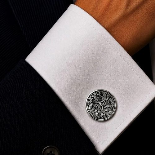 A circular pewter cufflink featuring an intricate Celtic triskele triple spiral design with antiqued recessed details