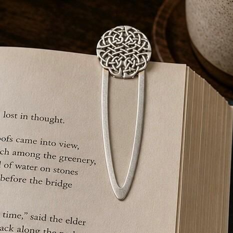 Handcrafted pewter Celtic knot metal clip bookmark resting on open book page