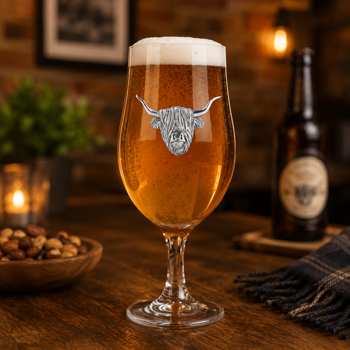 A beer goblet filled with beer. On the front is highland cow badge