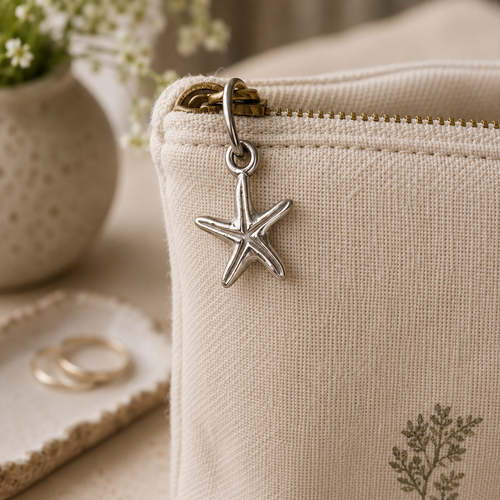 A pewter Starfish charm hanging on a soft fabric