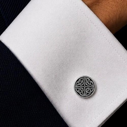 A circular pewter cufflink featuring a four-quadrant Celtic knot design with blackened antiqued recesses