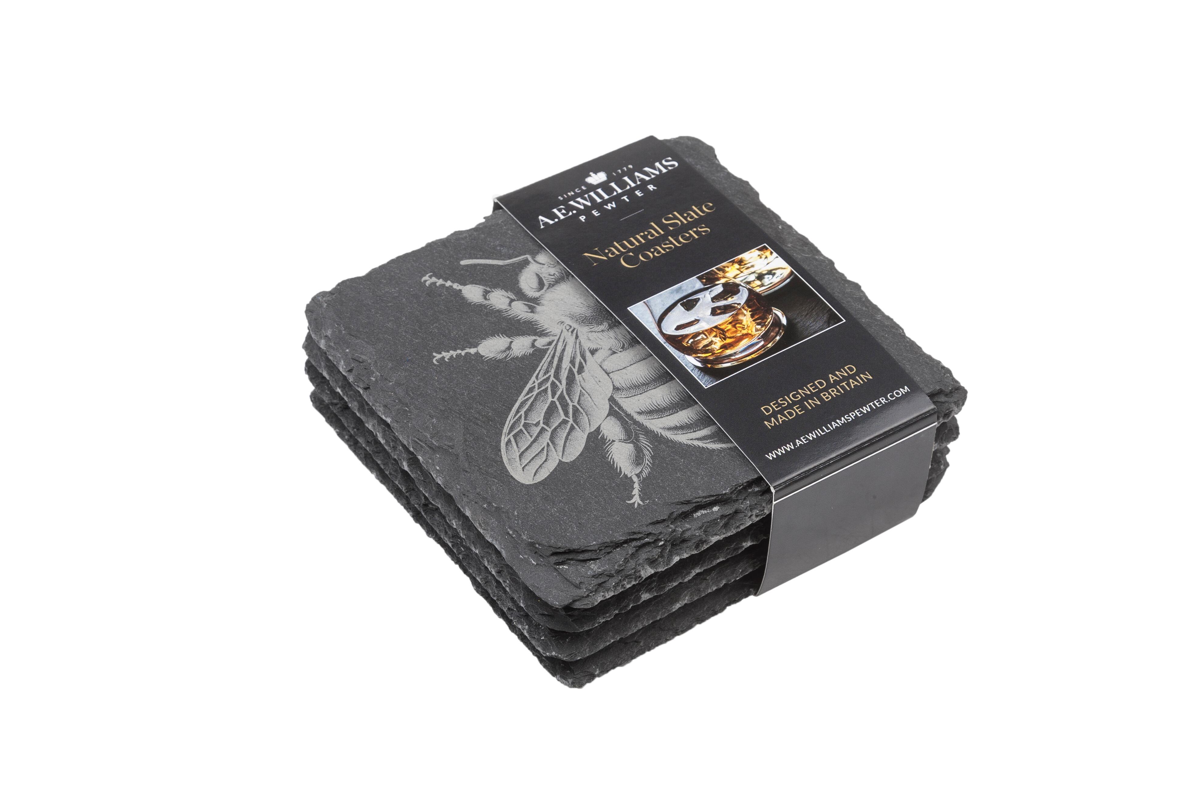 The top coaster features an engraved bee design. A product label wraps around the stack, displaying the brand name, product type 'Natural Slate Coasters', and an image of a whiskey glass on a coaster. The label states 'Designed and Made in Britain' and includes the company website.