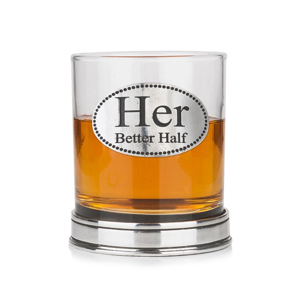 Whisky tumbler with pewter "Her Better Half" badge and polished base, partially filled with amber liquid