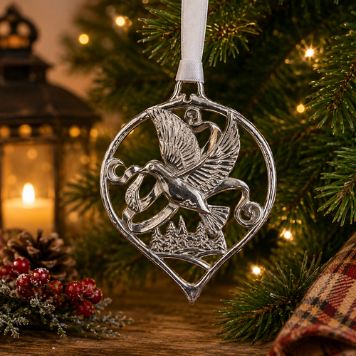 Handcrafted pewter dove Christmas ornament featuring a flying Turtle dove above a winter woodland scene, hanging on a festive Christmas tree with warm holiday lights and seasonal decorations.