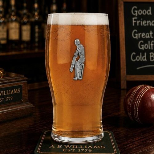 Pint glass with handmade pewter cricketer badge featuring batsman stance filled with golden beer