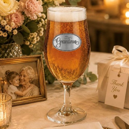 A Stemmed Pint Beer Glass with a Pewter Grandma badge on the front, filled with Beer