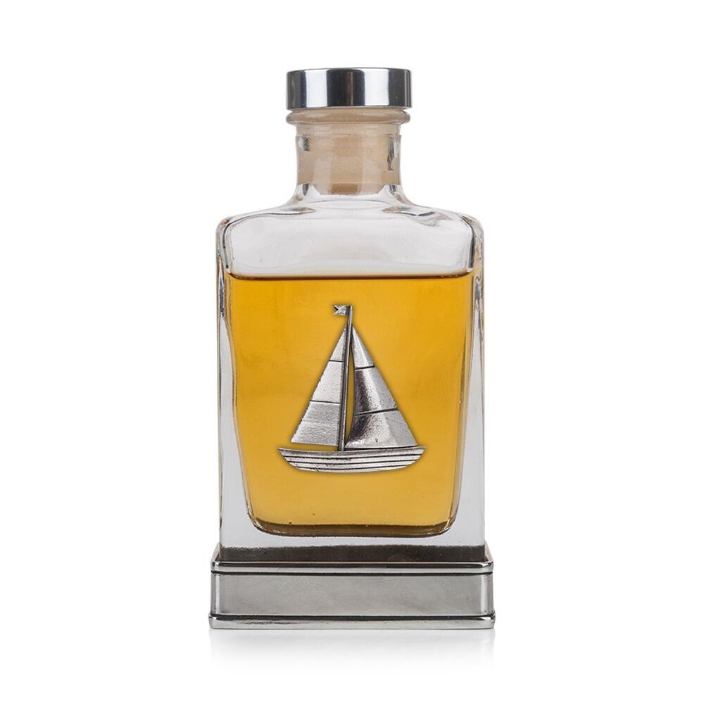 A glass flask with a pewter base and a handcrafted pewter sailing emblem on the front