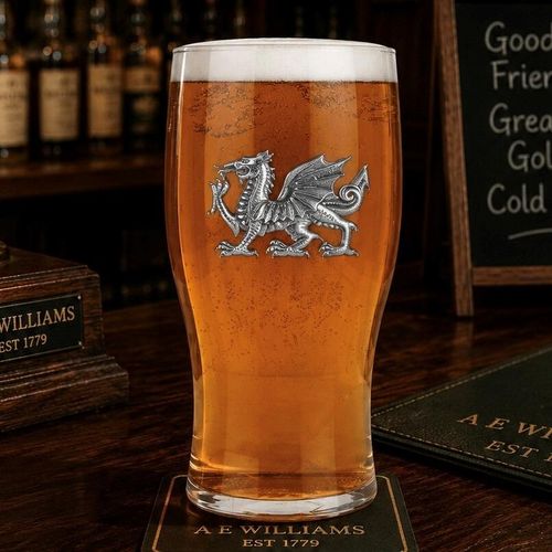 Pint glass with handmade pewter dragon badge featuring detailed scales and wings filled with golden beer