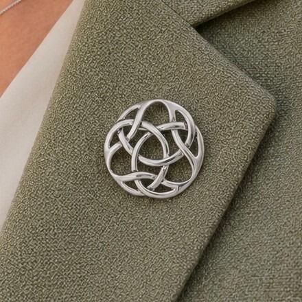 A circular pewter brooch featuring a smooth, openwork Celtic knot design