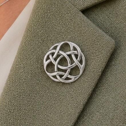 A circular pewter brooch featuring a smooth, openwork Celtic knot design