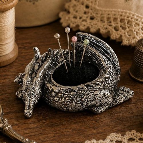 Detailed pewter coiled dragon pincushion figurine with a black fabric cushion holding four colorful pearl-head pins