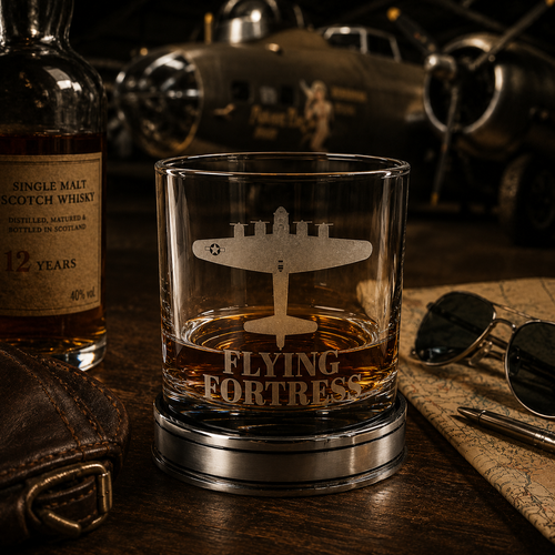 Handcrafted pewter Flying Fortress whisky tumbler with engraved B-17 bomber design, filled with whisky on a polished pewter base in a vintage WWII aircraft hangar setting, luxury British made aviation whisky glass gift